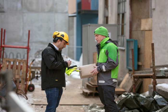 kurer leverer en pakke til en byggeplads