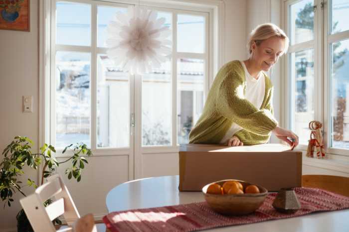 En kvinde står med en pakke på et bord foran sig
