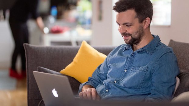 en mand sidder på sofaen med sin bærbare computer
