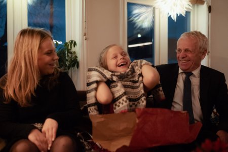 Glad pige åbner julegave købt på Black Friday sammen med sin bedstefar og søster