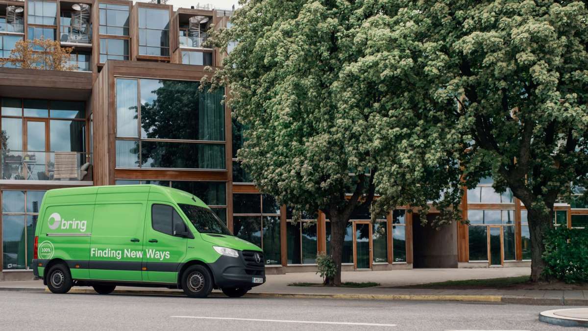 En Bring budbil står ved siden af ​​et hus og et træ