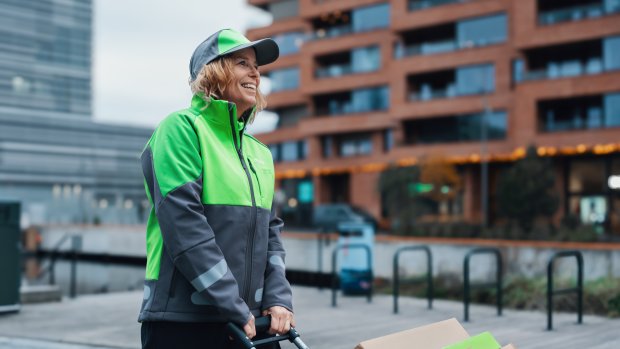 En kvindelig Bringbud trækker en vogn med pakker på gennem byen