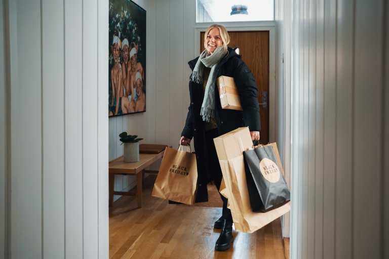 En kvinde går i hallen med en masse tasker i hænderne, hvor der står Black Friday