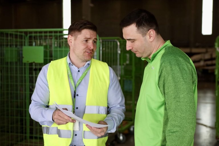 En mand som viser en mandlig kollega et stykke papir med kvalitetsmålinger