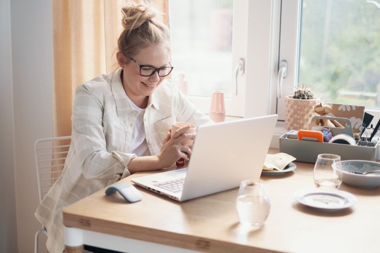 Kvinde smiler og kigger på laptop