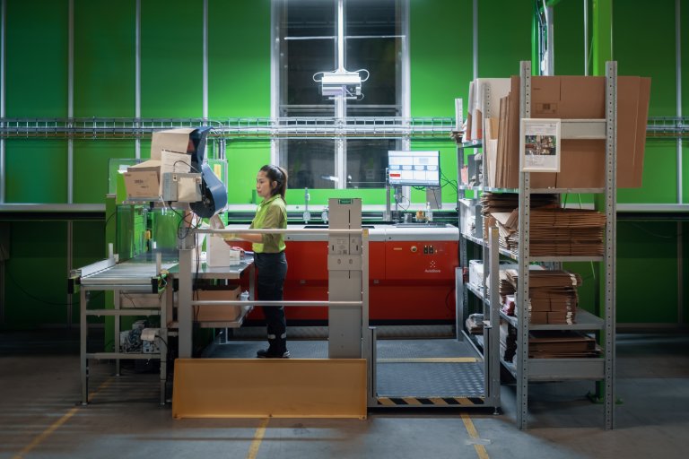 Kvinde står foran en pakkestation i autostore