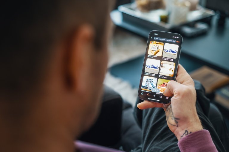 En mand sidder med en telefon i hånden og skal til at handle online fra en webshop
